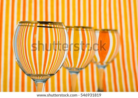 orange striped background, in front 3 water glasses