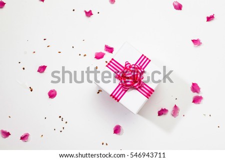 White gift box with pink ribbon and plum petal