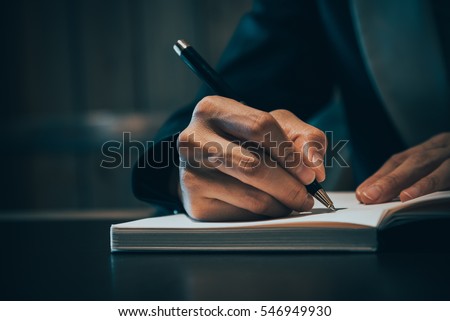 Close up of business people hand in suit writing on notebook or document Royalty-Free Stock Photo #546949930