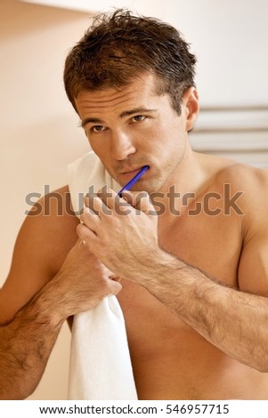 Reflection in a bathroom mirror of a young man brushing his teeth