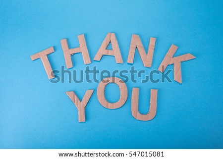 Inscription THANK YOU made from cardboard letters on a blue background made photo from top. High definition.