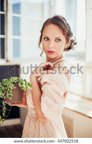 Beautiful woman wearing long dress holding house plant.