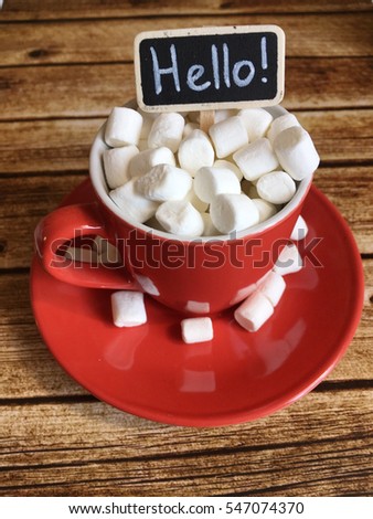 Valentines morning coffee in a red cup with marshmallows on wooden background. valentines morning cocoa with marshmellows and a chalkboard hello. hello valentines morning coffee in a red cup 