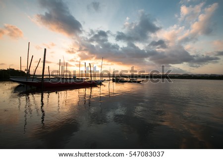 Sunset with fishing canoes on the river and with blue sky and clouds