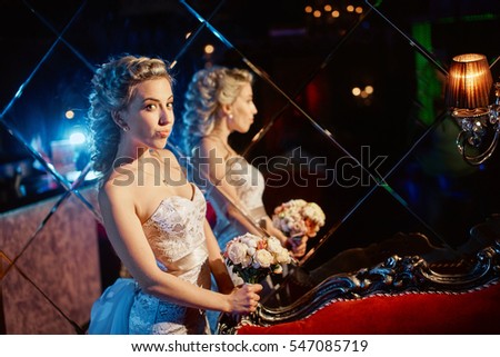 Beautiful blond bride posing in the luxury restaurant. The dark background.