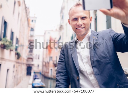 Smiling man take a selfie tourist photo on the Venice chanel background