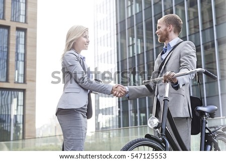 Happy businesspeople shaking hands outside office building Royalty-Free Stock Photo #547125553