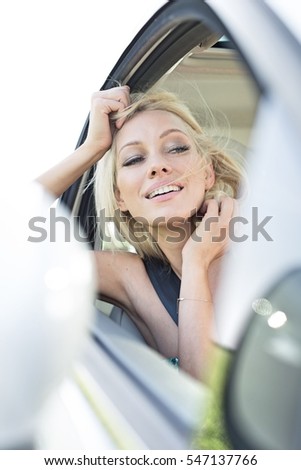 Happy young woman leaning on car window