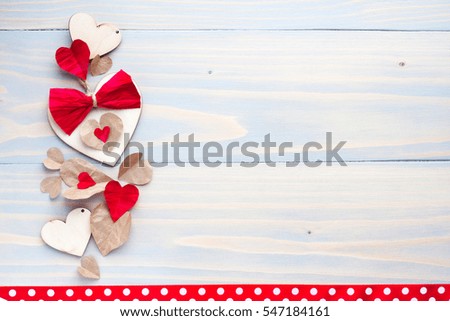 Happy Valentines day photo card background. Blue wooden table and natural material hearts with red bows hipsters background birthday women's day party celebrations decor objects cute polka dots ribbon