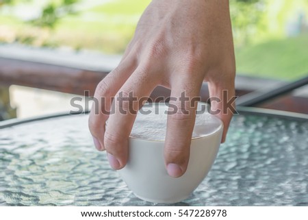 Selective focus at hand's man holding coffee mug with a lot of milk foam. Loving coffee concept.