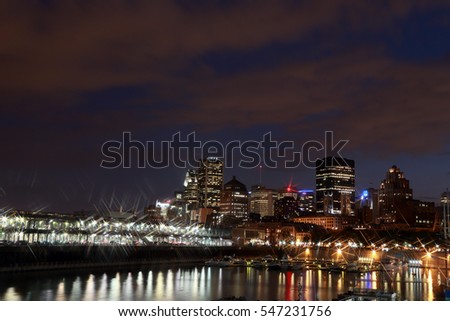 Montreal Downtown Panorama at night. Montreal reflected in water at dusk with city lights and urban buildings. Night city lights reflected in the water. Quay in the colorful bright lights with rays.