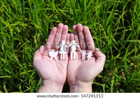 Cut paper with the logo of family on hands over green plant background, 