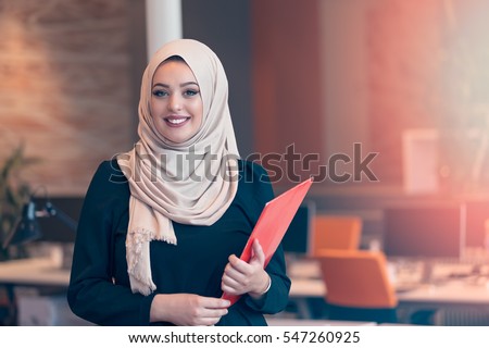 Arabian business woman holding a folder in modern startup office Royalty-Free Stock Photo #547260925