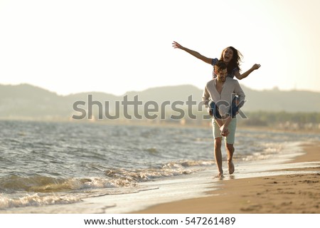 A guy carrying a girl on his back, at the beach, outdoors Royalty-Free Stock Photo #547261489
