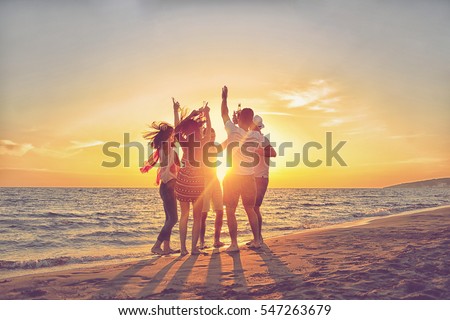 group of happy young people dancing at the beach on beautiful summer sunset Royalty-Free Stock Photo #547263679
