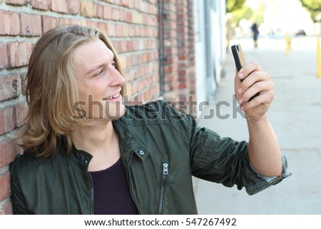 Beautiful young man in casual clothes make selfie on a background of red brick wall