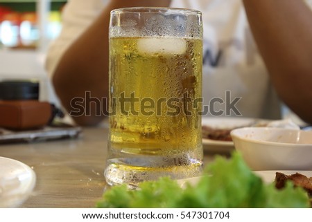 Beer Mug on brown table, golden of beer contrast with white cool of ice