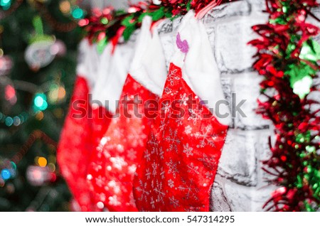 A close picture of beautifully decorated bright red Christmas socks hanging on a fireplace waiting for presents.