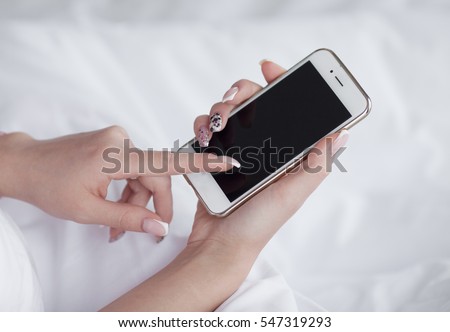 Closeup image of a teenager is searching information in network on mobile phone during free time. Young female student is revising photos on her cell telephone during break between lectures