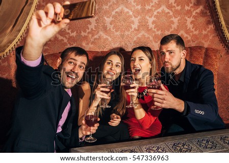 two beautiful couples at the party take a selfie with glasses