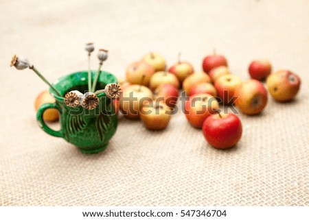 Small, red apples with burlap texture in the background