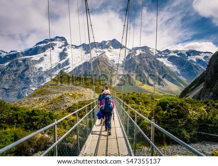 Amazing Nature of Hooker Valley Track in Mount Cook, New Zealand. Young Family walk on Suspension Bridge. Royalty-Free Stock Photo #547355137