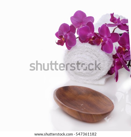 pink orchid on towel, wooden bowl on white