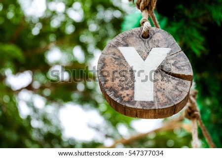 White Y alphabet on brown wood decorate with green blurred tree , bokeh background