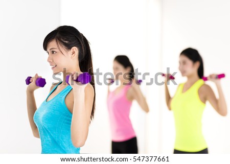 young woman doing exercise with dumbbell in gym