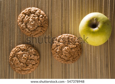 Three oatmeal cookies with apple on a bamboo mat. Flat lay
