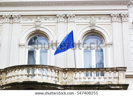 European Union flag fluttering in balcony of house on background of two large arched windows
