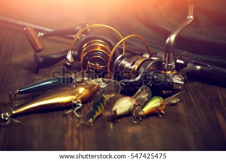Fishing tackle - fishing spinning, hooks and lures on darken wooden background. Royalty-Free Stock Photo #547425475