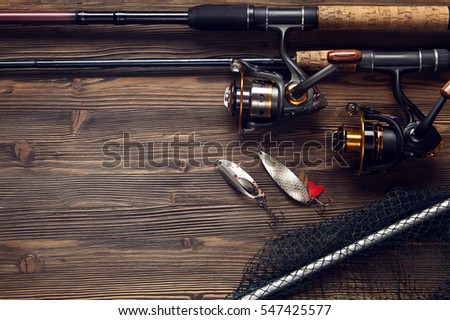 Fishing tackle - fishing spinning, hooks and lures on darken wooden background.Top view. Royalty-Free Stock Photo #547425577