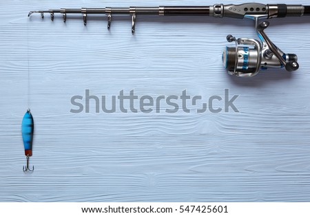 Fishing tackle - fishing spinning, hooks and lures on light wooden background.Top view. Royalty-Free Stock Photo #547425601