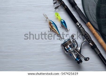 Fishing tackle - fishing spinning, hooks and lures on light wooden background.Top view. Royalty-Free Stock Photo #547425619