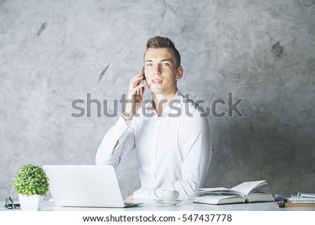 Portrait of handsome young guy talking on mobile phone at workplace