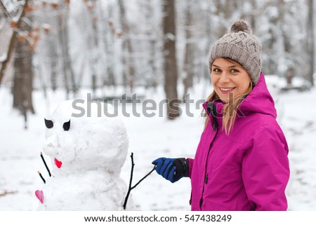 Picture of a cute girl posing next to a snowman