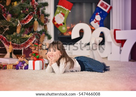 Portrait of a nice little girl by the fireplace. Christmas motif.