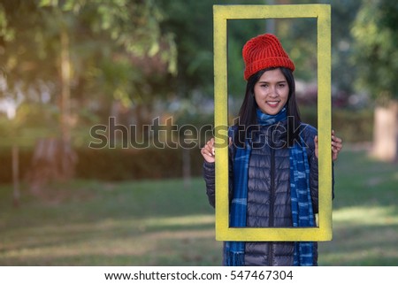 Beautiful woman with yellow frame in a park during the winter.
