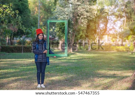 Beautiful woman with green frame in a park during the winter.
