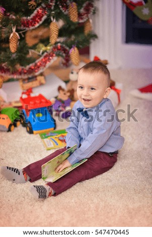 Portrait of a little boy near Christmas tree with gifts. Christmas motif.