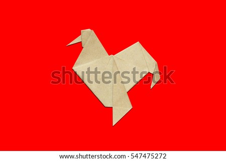 Paper folded rooster handmade origami craft on red background. 2017 is year of the Rooster.