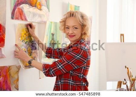 Senior female artist hanging picture in studio