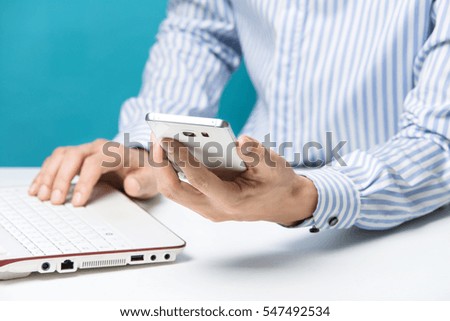 Male hands, Notebook and smart-phones for business in the office on blue background