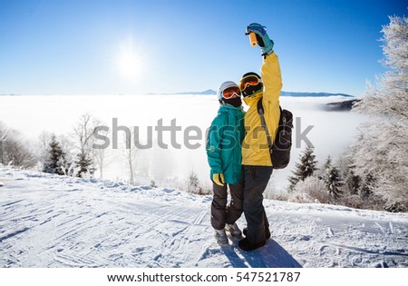 Skiers taking picture of themselves with smart phone over a mountain