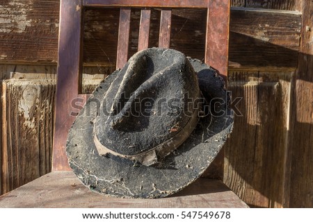 Battered old hat damaged by clothes moth on vintage background. A forgotten hat covered with spider web among the ruins of a house. Imagine the owner of this hat and tell their story.