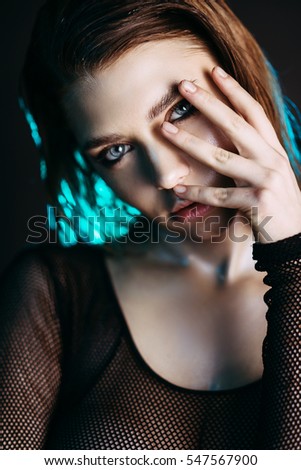 Fashion model beautiful girl in fashionable clothes in ultraviolet light, showing different poses. Beauty body and face. Photos shot in studio. Advertising Space