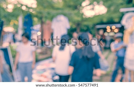 Blurred image of people walking at day market  in garden with bokeh for background usage . (vintage tone)