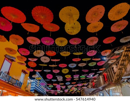 Colorful umbrellas hanging from building creating feeling of floating umbrellas in the night skies. Long shutter speed used lead to noise, blurred subject and soft focus when view at full resolution.