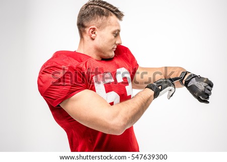American football player in uniform pointing on smartwatch isolated on grey
